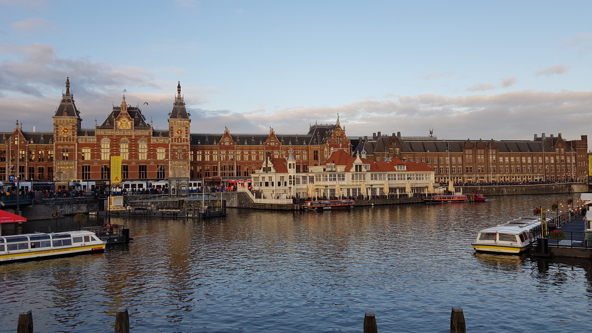 Amsterdam Centraal am Wasser mit Ausflugsbooten