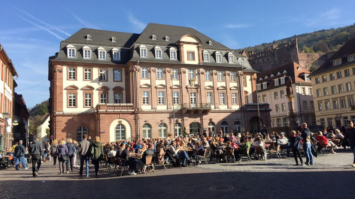 Belebter Kornmarkt in Heidelberg mit Palais Graimberg und Schlossruine
