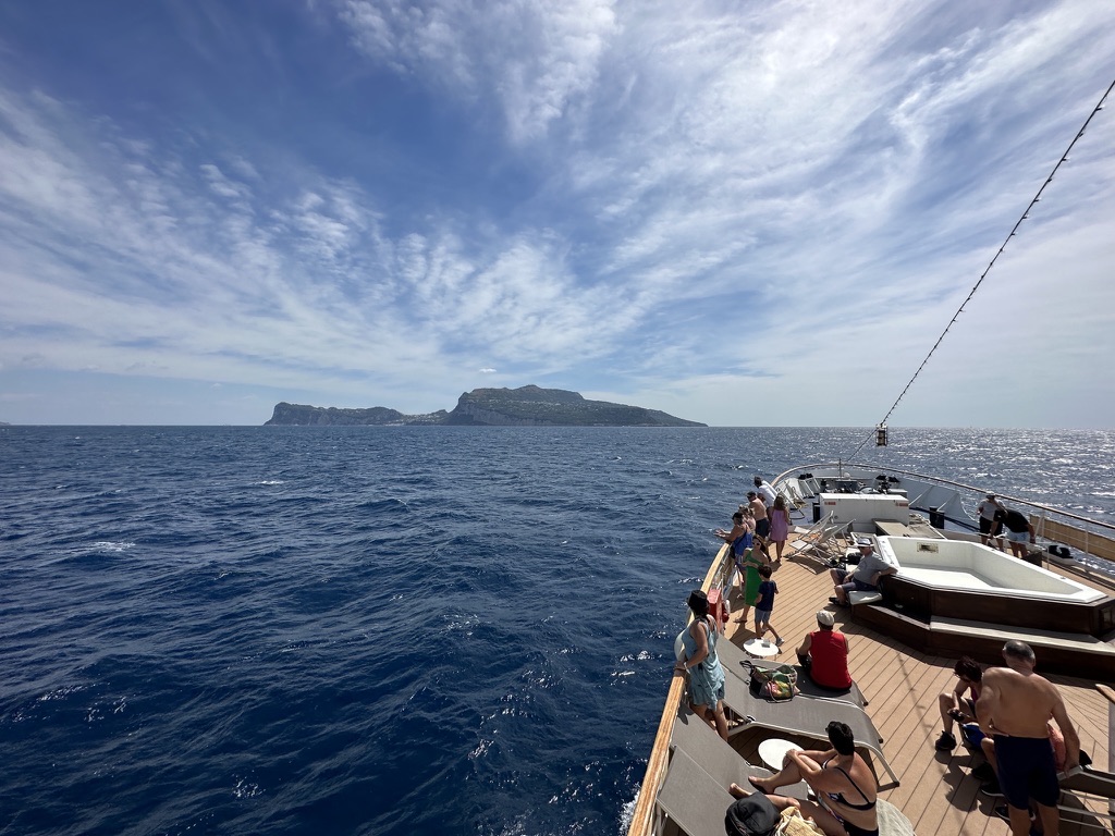 Blick vom Kreuzfahrtschiff über das Meer auf eine felsige Inselküste