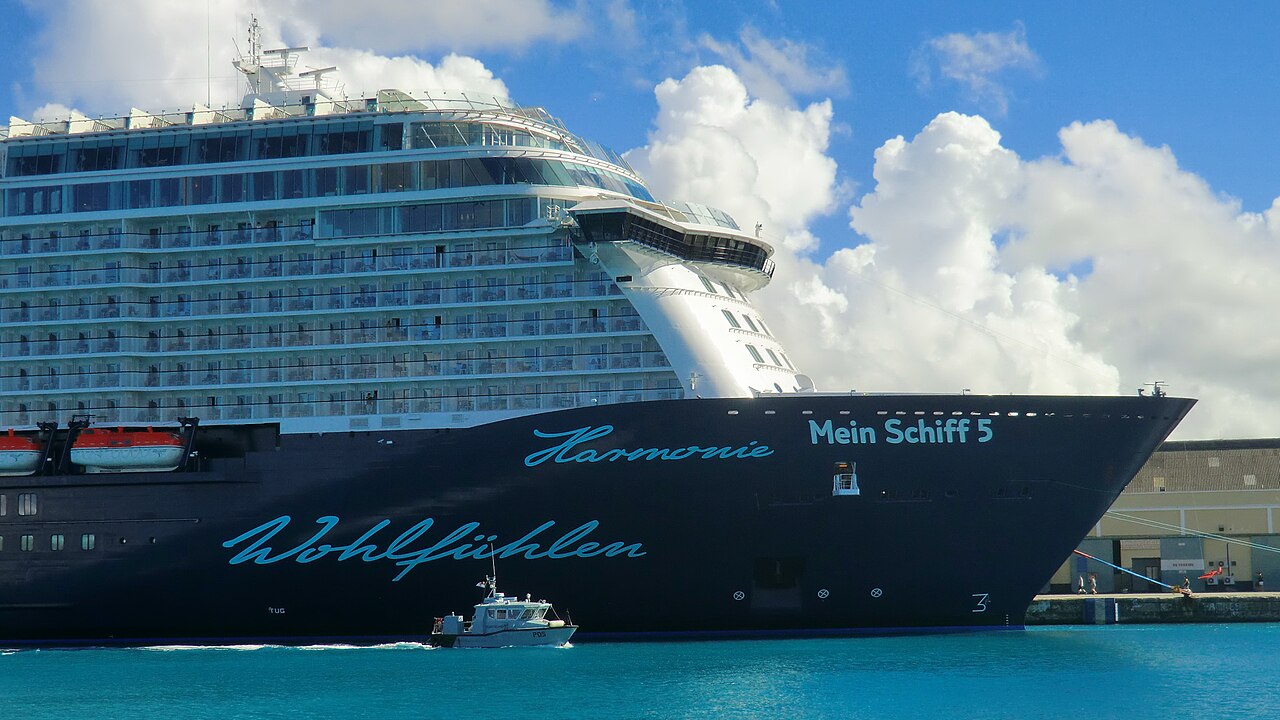 Mein Schiff 5 im Hafen von Bridgetown mit kleinem Boot und türkisblauem Wasser
