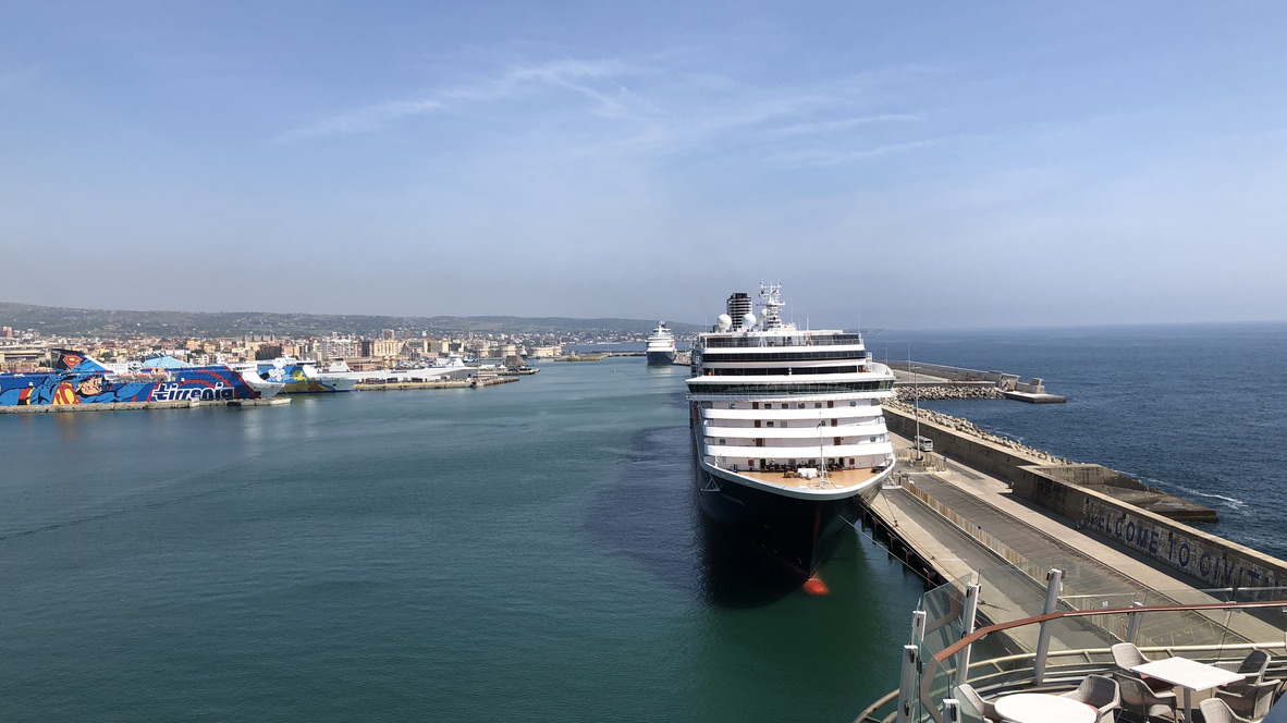 Hafen von Civitavecchia mit einem Kreuzfahrtschiff am Kai und Fähren vor der Stadt