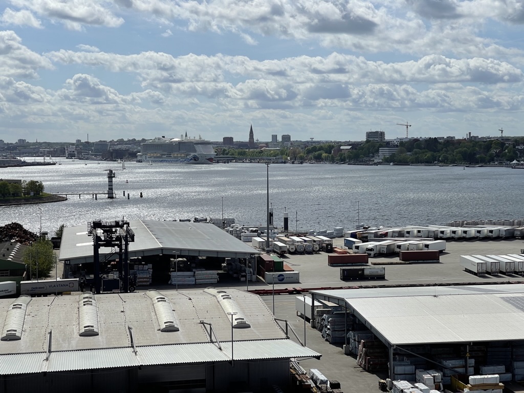 Blick über die Kieler Förde mit Hafenanlagen und Kreuzfahrtschiff