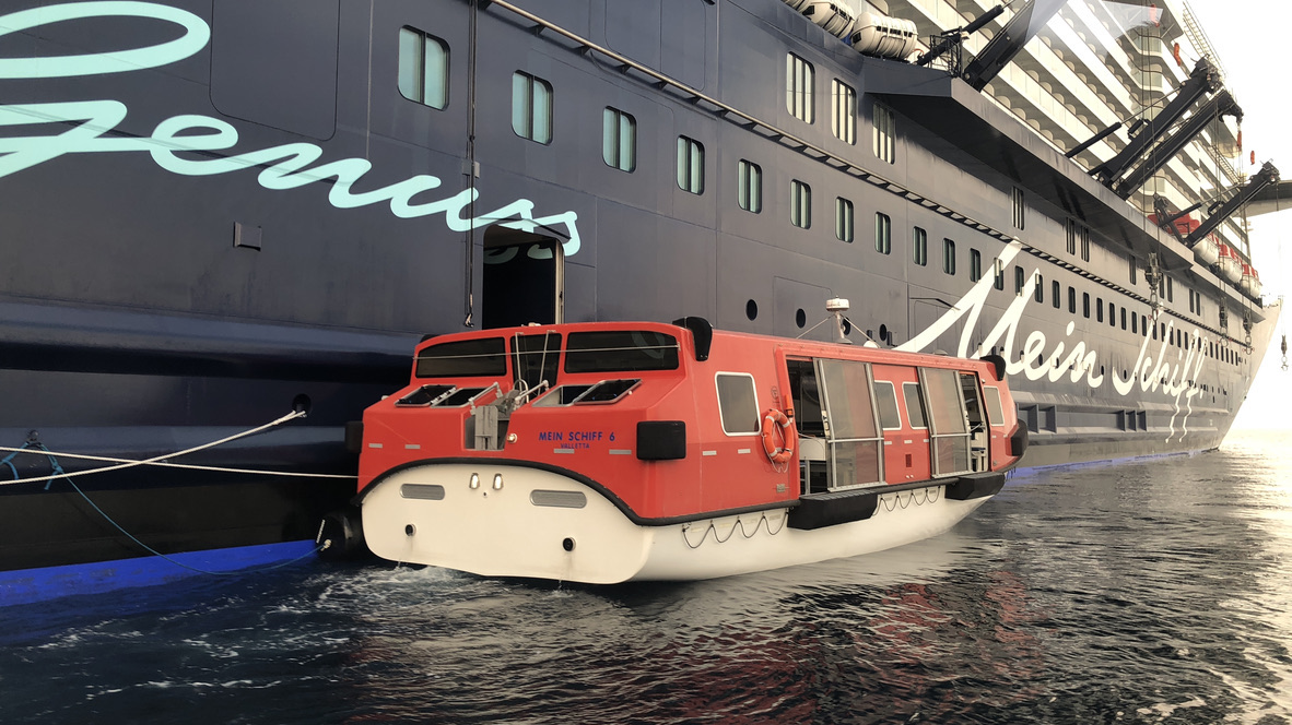 Rotes Tenderboot neben einem Kreuzfahrtschiff der Mein-Schiff-Flotte