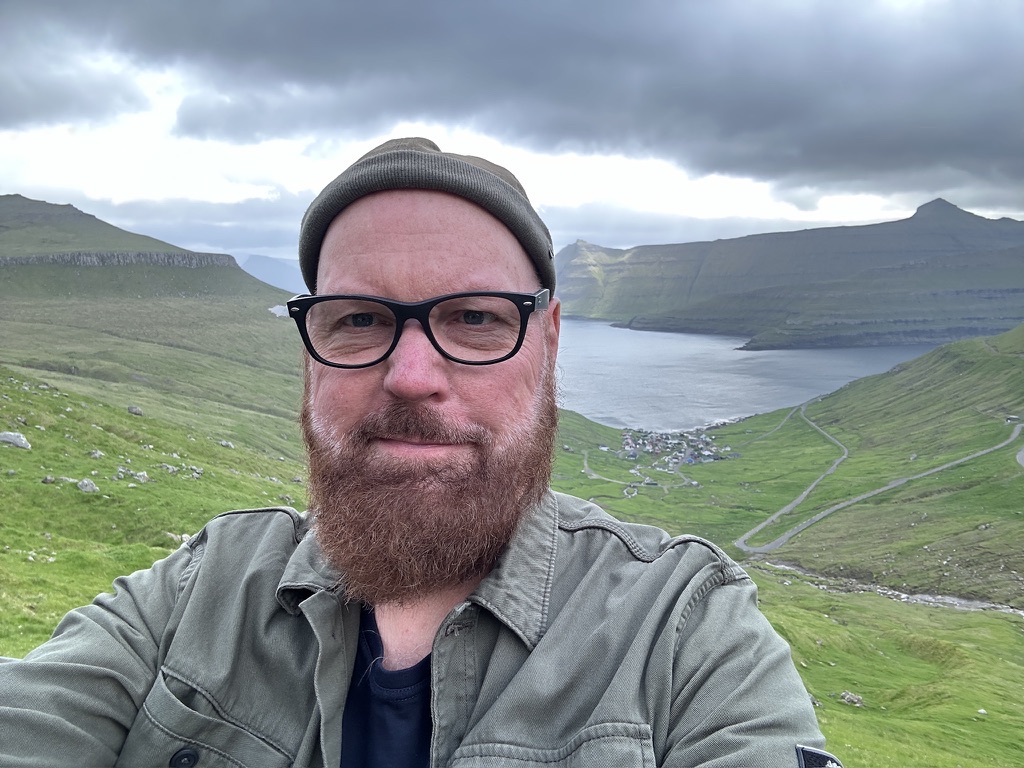 Hans-Mario Praetor vor einem Fjord und grünen Hängen auf den Färöern