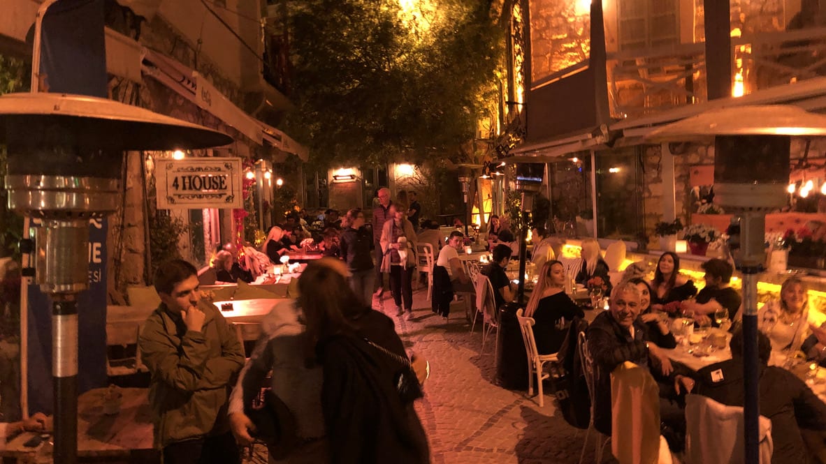 Belebte kleine Restaurantgasse in Çeşme am Abend