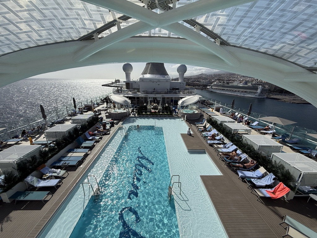 Pooldeck eines Kreuzfahrtschiffs mit Liegen und Blick über den Hafen