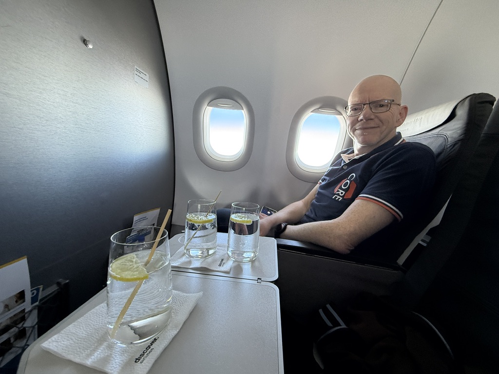 Reisender am Fenster in der Business Class auf einem Kurz- oder Mittelstreckenflug, davor ein gedeckter Tisch