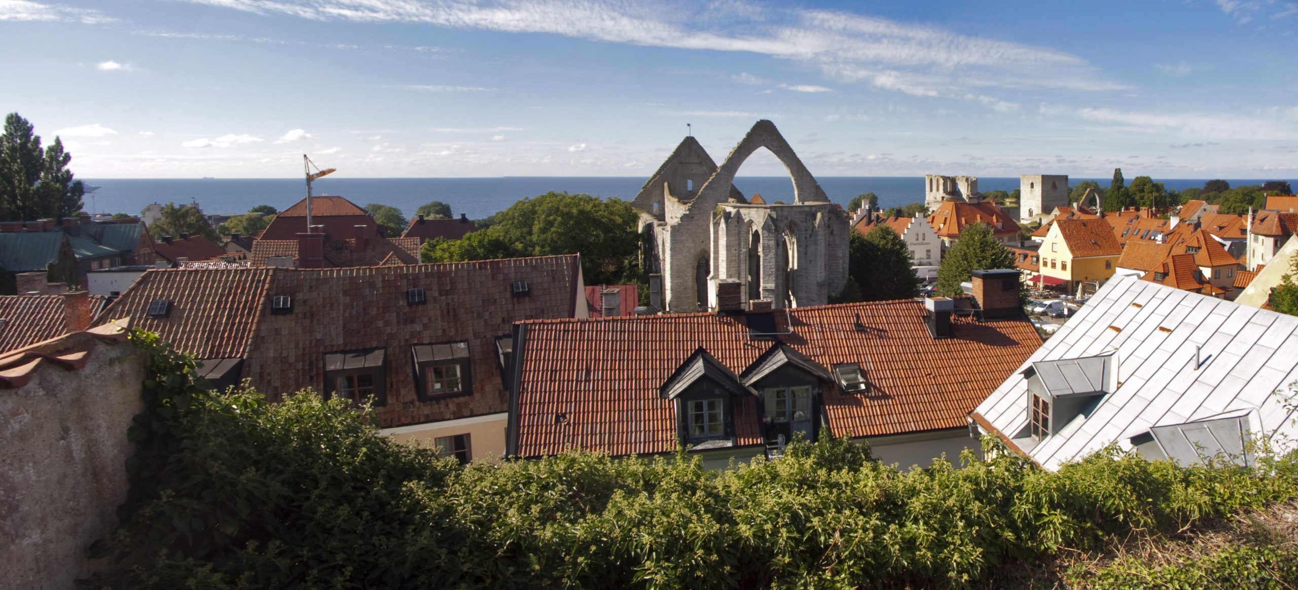 Rote Dächer der Altstadt von Visby mit Kirchenruine und Ostsee im Hintergrund