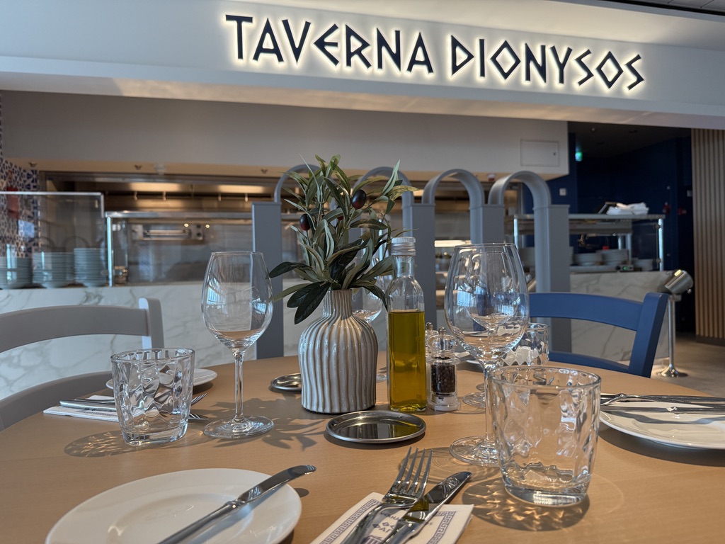 Gedeckter Tisch vor dem Schriftzug der Taverna Dionysos auf der Mein Schiff Relax